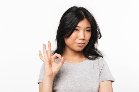 Image of asian beautiful young woman posing isolated over white wall background showing okay gesture.の写真素材