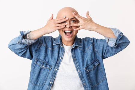 Image of a beautiful happy bald woman posing isolated over white wall background covering face with hands.の写真素材