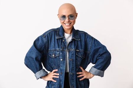 Portrait of a beautiful young hairless woman wearing casual clothes standing isolated over white background, hands on hipsの写真素材
