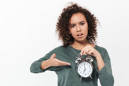 Portrait of a pretty tired casual african girl standing isolated over white background, showing...