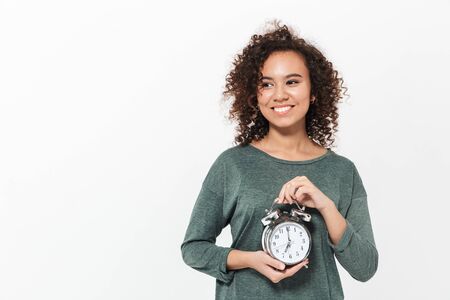 Portrait of a pretty cheerful casual african girl standing isolated over white background, showing...