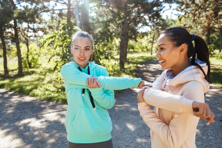 Attractive smiling fitness woman wearing hoodies working out at the parkの写真素材