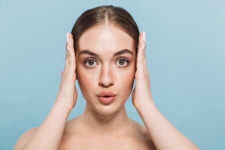 Portrait of a pretty young woman posing isolated over blue wall background.の写真素材