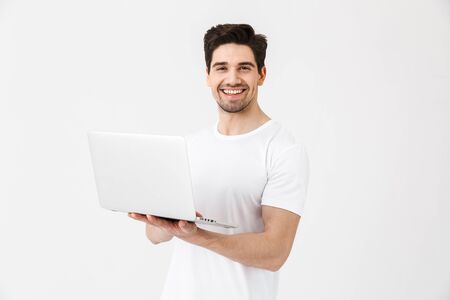 Image of happy excited young man posing isolated over white wall using laptop computer.の写真素材
