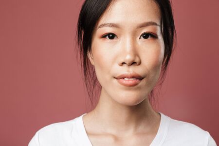 Portrait of beautiful asian woman dressed in basic wear smiling and looking at camera with lovely...