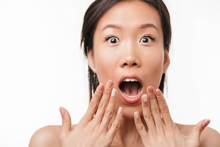Image of a beautiful shocked excited asian young pretty woman with healthy skin posing isolated over white wall background.の写真素材