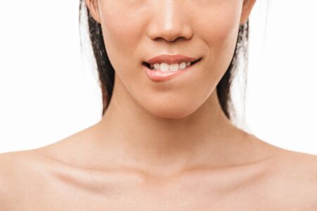 Cropped photo of a young beautiful asian woman posing isolated over white wall background bite lip.の写真素材
