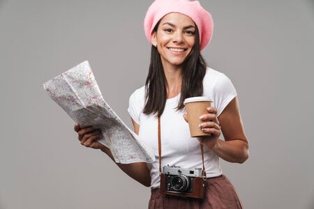 Image closeup of kind young tourist woman with retro vintage camera and takeaway coffee smiling and holding paper map isolated over gray backgroundの写真素材