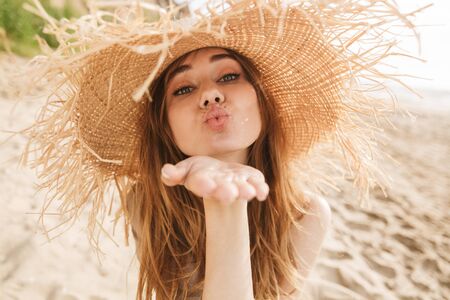 Portrait of young positive gorgeous attractive woman posing outdoors at the sea beach blowing kisses.の写真素材