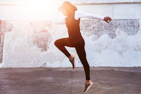 Image of a young concentrated muslim sports fitness woman dressed in hijab and dark clothes posing...