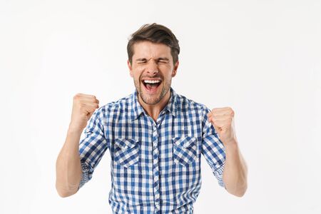 Photo of excited man in plaid shirt screaming and rejoicing with fists clenched isolated over white backgroundの写真素材