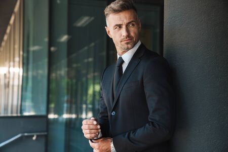 Photo of a serious mature handsome grey-haired business man outdoors at the street near business center.の写真素材