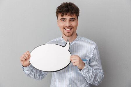 Portrait of unshaved beautiful man dressed in shirt holding blank copyspace thought bubble isolated over gray backgroundの写真素材