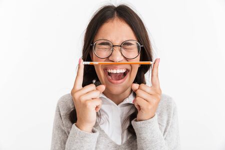 Image of excited emotional screaming young school girl isolated over white wall background holding pencil.の写真素材