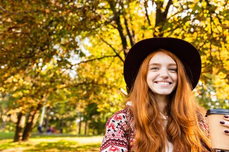 Image of optimistic cheerful smiling happy young student redhead girl in autumn park walking.の写真素材