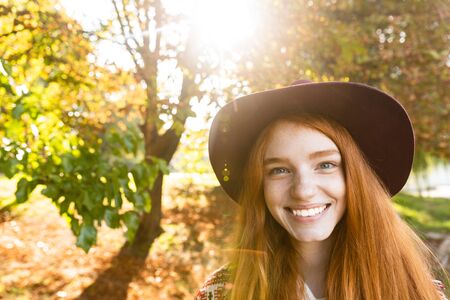 Image of smiling cheerful young student redhead girl in autumn park walking.の写真素材