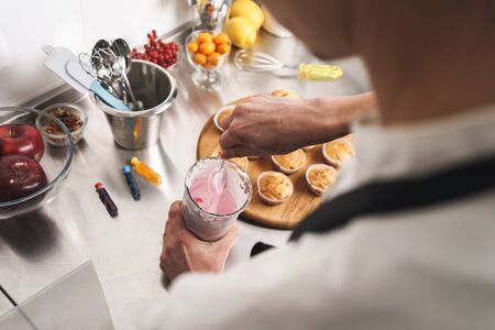 Cropped photo of a handsome young cook chef at the kitchen cooking sweeties indoors.の写真素材
