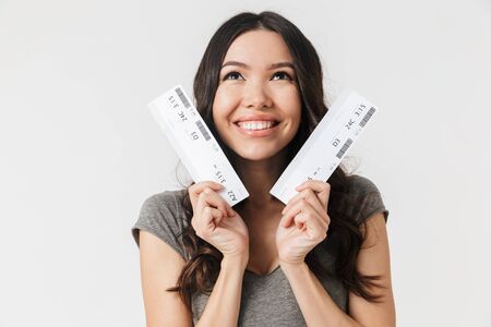 Image of a beautiful excited happy young woman posing isolated over white wall background holding...