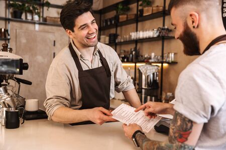 Close up of a customer paying at the coffee shop counter with credit cardの写真素材