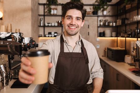 Image of handsome happy coffee man posing in cafe bar working indoors holding coffee cup.の写真素材