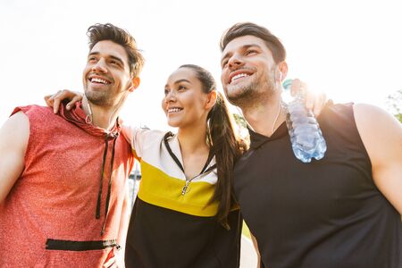 Photo of happy joyful people wearing sportswear smiling and hugging while working out outdoorsの写真素材