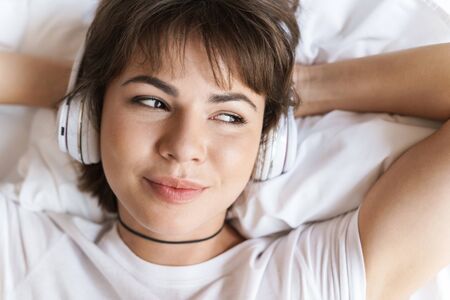 Photo of a dreaming thinking optimistic positive pleased young beautiful woman lies indoors at home...