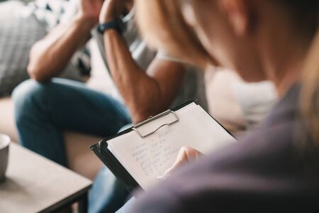Photo cropped of brooding handsome man having conversation with psychologist on therapy session in...