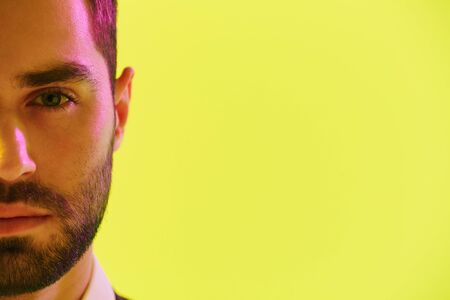 Half-side image of concentrated businessman in formal suit looking at camera with copyspace isolated over yellow backgroundの写真素材