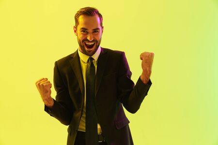 Image of happy young businessman in formal suit screaming and gesturing with triumph isolated over...