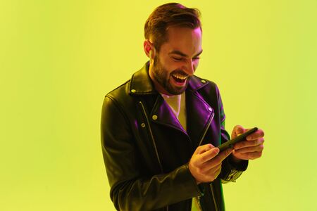 Image of emotional young stylish man isolated over light green background wall with led neon lights...