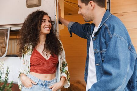 Portrait of smiling couple man and woman talking together while standing near house on wheels...