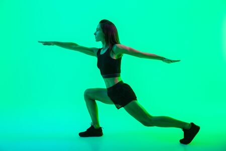 Full length of a beautiful young fitness girl working out isolated over green background, doing lungesの写真素材