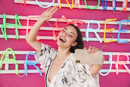 Image of a smiling optimistic young pretty woman at the beach party with bright led colorful...