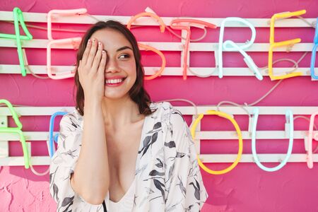 Image of a smiling young pretty woman at the beach party with bright led colorful background having...