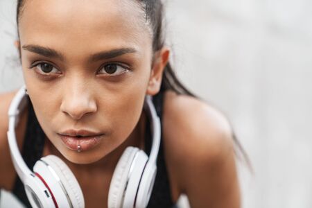 Close up of an attractive young fitness girl resting after workout while standing outdoorsの写真素材