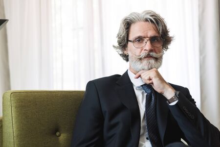 Portrait closeup of caucasian mature businessman wearing black suit and eyeglasses looking at camera...