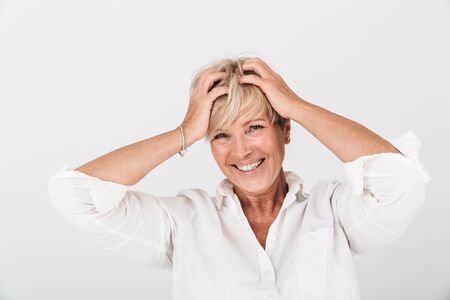 Portrait of delighted adult woman with short blond hair grabbing her head and laughing at camera...