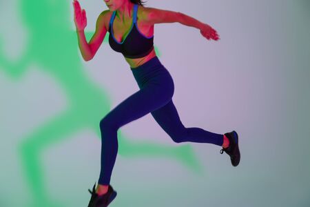Cropped image of young fitness woman isolated with led flash lights running.
