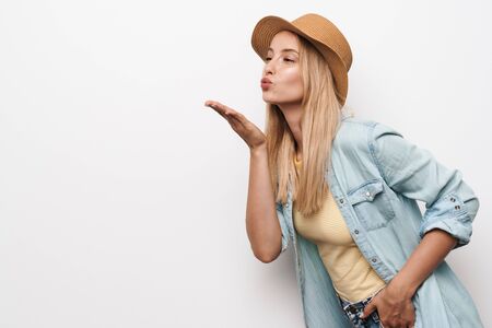 Photo of pleased amazing young pretty woman wearing hat posing isolated over white wall background blowing kisses.の写真素材