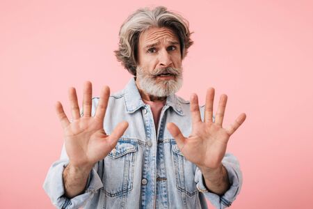 Portrait of a shocked middle aged man wearing casual outfit standing isolated over pink background