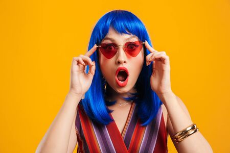 Portrait of an attractive funky young girl with blue hair wearing casual outfit standing isolated...