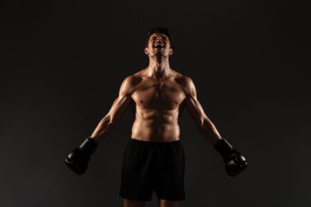 Image of a concentrated strong handsome young sportsman boxer in gloves posing isolated over black wall background.の写真素材