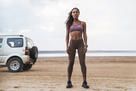 Attractive young african fitness woman standing at the beach