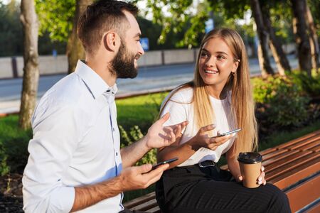 Photo of a cheerful optimistic young business colleagues man and woman talking with each other using...
