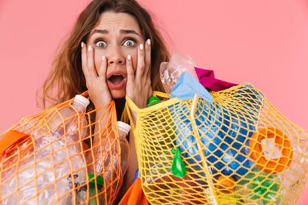 Photo of shocked scared woman in basic t-shirt holding bags with plastic waste and looking at camera...