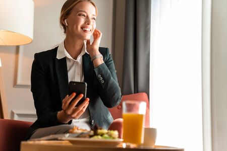 Photo of a young beautiful cheerful optimistic blonde business woman sit indoors have a dinner.の写真素材