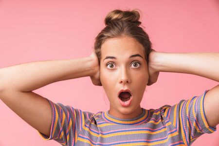 Image closeup of surprised beautiful woman screaming and covering her ears with hands isolated over...