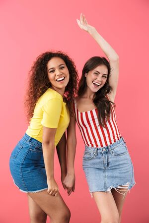 Image of attractive multinational girls smiling together at camera isolated over pink backgroundの写真素材