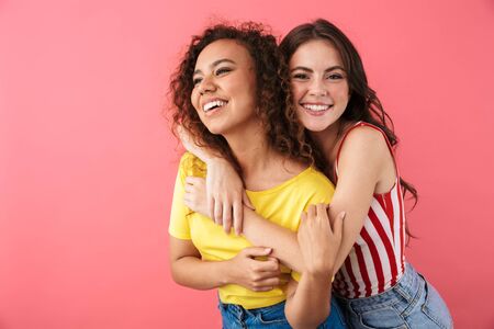 Image of cheerful multinational girls hugging and smiling together at camera isolated over pink backgroundの写真素材