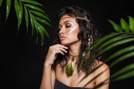 Beauty portrait of an attractive sensual young brunette woman wearing tribal accessories posing with...